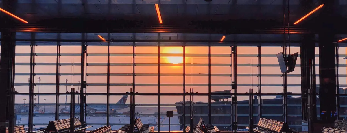 Sunset seen through the tall window wall of an empty airport terminal